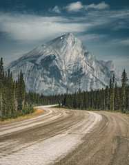 View of street highway with mountains and trees with blue sky and clouds. Banff National Park Canada Rocky Mountains.