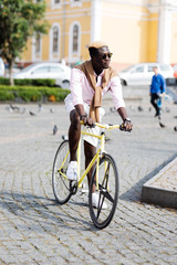 Handsome afro american man riding a bike in the street.