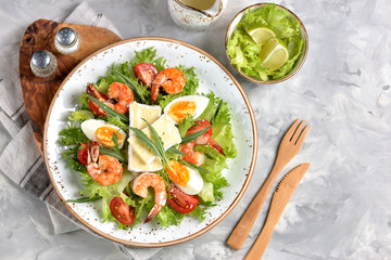 Healthy lettuce salad with arugula, large shrimps, cherry tomatoes, boiled egg, brie cheese and grated parmesan cheese.