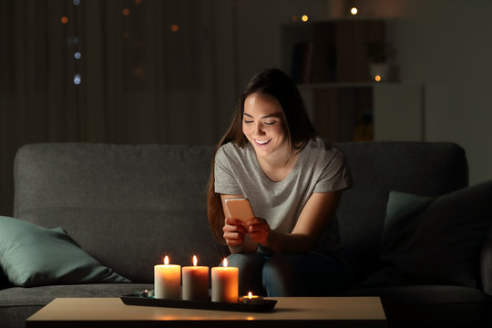Woman using a smart phone in the night with candle lights