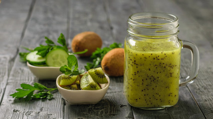 Freshly prepared smoothie of kiwi, Apple, mint and kiwi slices on the gray table.