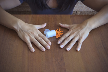 A depressed woman looks at the tablets on the table.