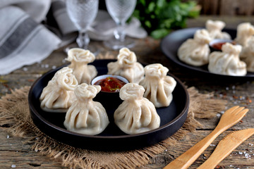 Georgian homemade khinkali (dumplings) with meat and red sauce on an old wooden background. Rustic style.