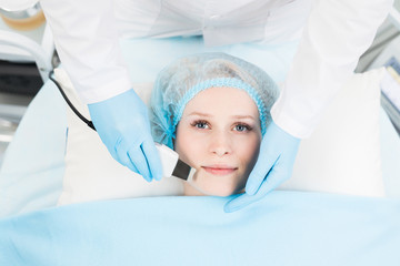 Naklejka premium Cosmetician of contemporary clinic or spa salon making soft beauty procedure on client face with electric device