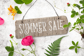 summer sale announcement / promotion with rustic wooden sign and colorful garden flowers on a white...