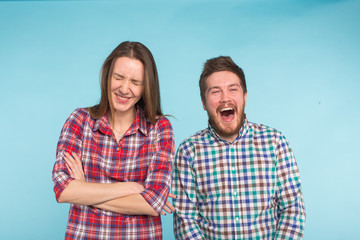 Funny young couple laughing and fooling around together on blue background.