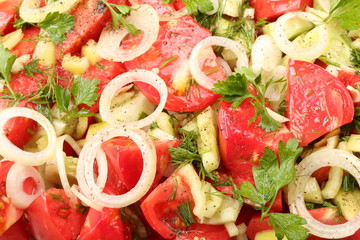 Sliced tomatoes, cucumbers, parsley leaves and dill, spices and olive oil. Fresh vegetable salad close-up