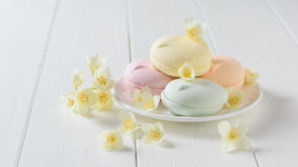 Colorful macaroons with Jasmine flowers on a white table.