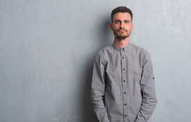 Young adult man standing over grey grunge wall depressed and worry for distress, crying angry and afraid. Sad expression.