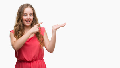 Obraz premium Young blonde woman wearing pink dress very happy pointing with hand and finger