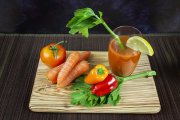Tomate juice with pepper, carrot and lemon on wood plank