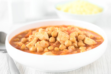 Frischer hausgemachter Eintopf aus Hähnchen und Kichererbsen, Couscous im Hintergrund, fotografiert mit natürlichem Licht (Selektiver Fokus, Fokus in die Mitte des Bildes)