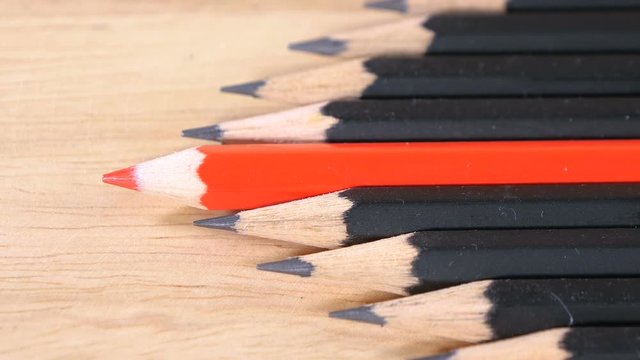 Motion video of red color pencil stand on black pencil with wood background (Leadership concept)