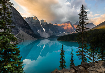 Sunrise with turquoise waters of the Moraine lake with sin lit rocky mountains in Banff National...