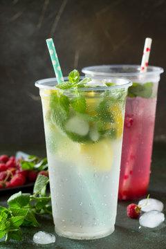 SOFT DRINKS. Refreshing summer drink lemon with mint, ice and raspberry with basil, ice. Glasses with cold and healthy beverage on a stone or slate gray background.