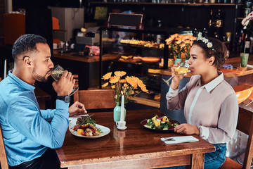 Beautiful African-American couple in love having a great time together at their dating, an attractive couple enjoying each other, eating in restaurant.