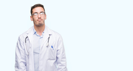 Fototapeta premium Handsome young doctor man smiling looking side and staring away thinking.