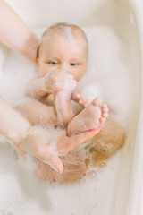 Happy little baby a swimming in the bathroom.Portrait of baby bathing in a bath with foam