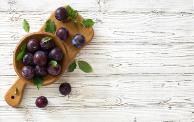 Ripe plums in wooden bowl. Top view