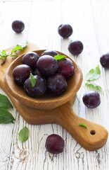 Ripe plums in wooden  bowl close up