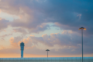 View of the airport air traffic control tower against the beautiful blue orange sky at sunset