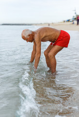 Happy mature man checks the water temperature