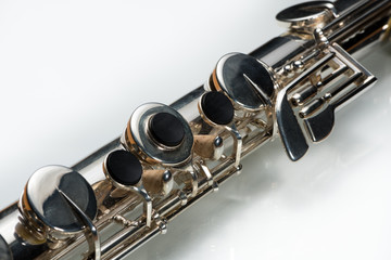 Obraz premium A silver bass flute lying on a white reflective surface