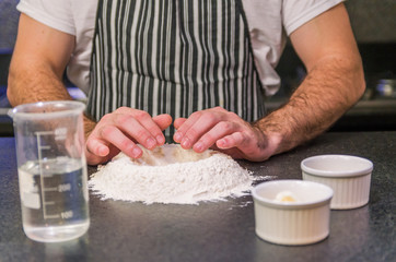 Man preparing pizza dough on black granite table