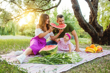 Young family on a picnic. Eat a watermelon and have fun together