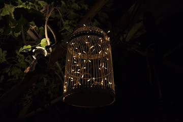 Decorative cage with garland lights in a bright night