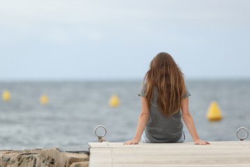Back view of a lonely teen looking at the ocean