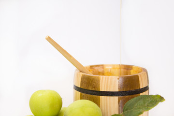 Wooden can with honey, green apples and leafs. (White background)