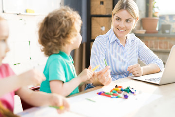 Happy mother playing with her two kids while working on laptop