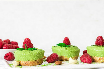 green matcha vegan raw cheesecakes with raspberries, mint and nuts. healthy delicious food