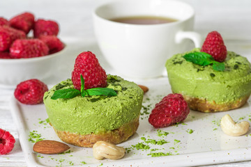 green matcha and banana vegan raw cheesecakes with raspberries, mint, nuts and coffee cup
