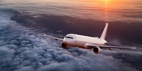 Commercial airplane flying above dramatic clouds. - obrazy, fototapety, plakaty