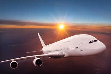 Big commercial airplane flying above dramatic clouds.
