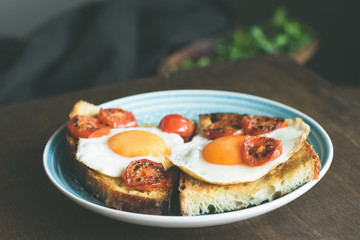 Breakfast Toast with sunny side up egg and tomatoes, closeup view, selective focus, toned image