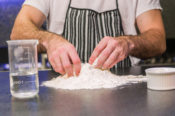 Man preparing pizza dough on black granite table