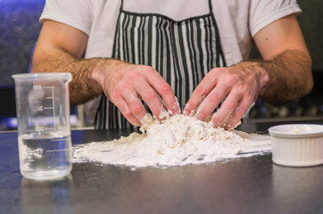 Obraz na płótnie Canvas Man preparing pizza dough on black granite table