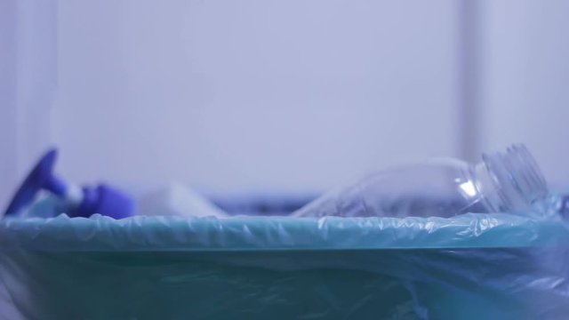 Housewife releasing place, getting rid of unnecessary bottles, thowing at bucket