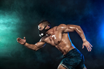 Fototapeta na wymiar Strong athletic man sprinter in training mask, running, fitness and sport motivation. Runner concept with copy space. Dynamic movement.