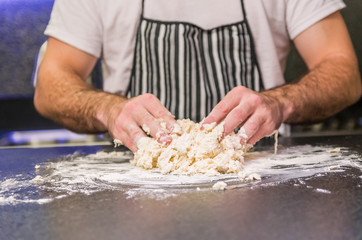 Man preparing pizza dough on black granite table