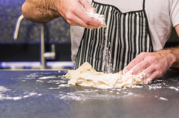 Man preparing pizza dough on black granite table