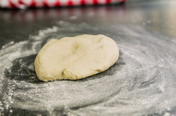 Mound of wheat flour on top of black granite table, preparation of pizza dough.