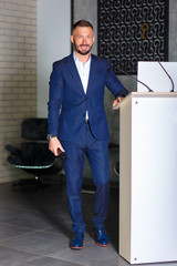 A man orator stands for the podium.Businessman in a suit behind the podium