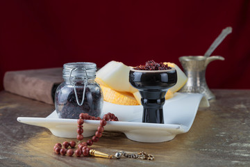 Shisha for hookah Smoking in a black glossy cup stands on a faience tray with melon on a Golden tablecloth