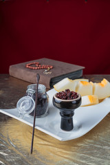 Shisha for hookah Smoking in a black glossy cup stands on a faience tray with melon on a Golden tablecloth