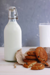 cookies with milk on dark back with craft paper bottle and glass of milk
