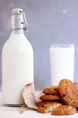 cookies with milk on dark back with craft paper bottle and glass of milk